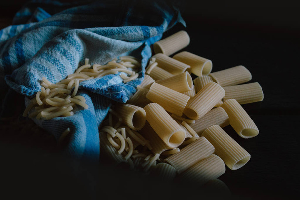 Delicious freshly made raw pasta prepared to be cooked. Fresh pasta on black slate background. - Foto, immagini