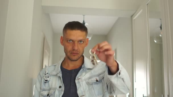 Porträt eines Mannes mit Schlüsseln aus einer neuen Wohnung. der Kerl ist glücklich, lustige Videos, Immobilien, Reparatur und Mietkonzept. die Schlüssel zur neuen Wohnung - Filmmaterial, Video