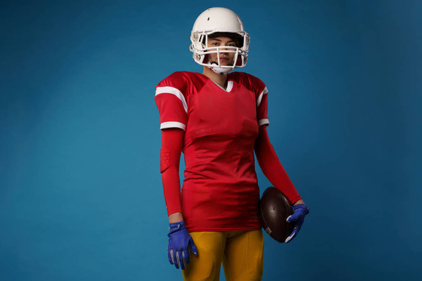 Image of american woman football player in white helmet, sportswear and ball in her hand - Foto, afbeelding