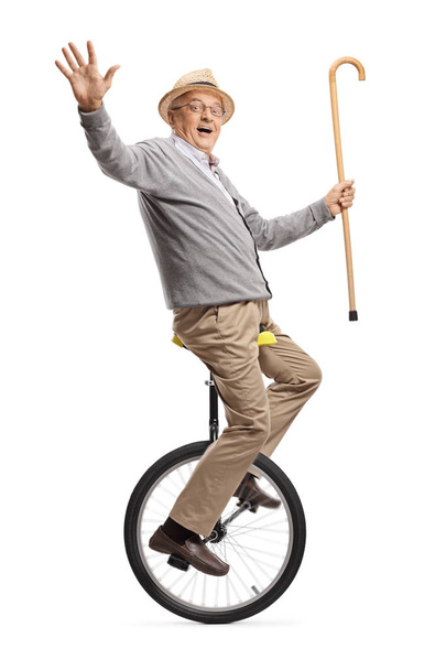 Senior man riding a mono-cycle and holding a walking cane - Foto, Imagen