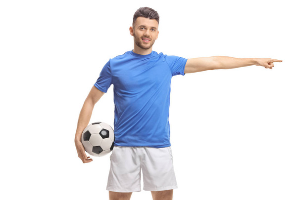 Soccer player holding a football and pointing to the side - Fotoğraf, Görsel