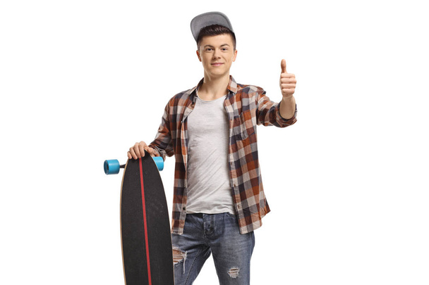 Male teenage with a longboard making a thumb up sign  - Фото, изображение