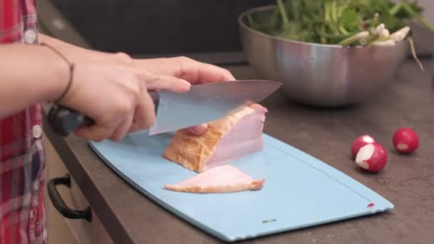 Young housewife slicing piece of smoked pork ham - Filmati, video
