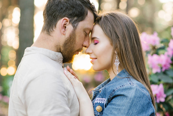Sensual young couple enjoys tender warm pleasant kind moment of love having romantic date, affectionate beautiful man and woman touching foreheads caressing adoring each other in nature spring, side Vie - Photo, Image