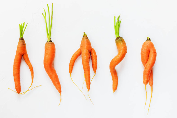 Ugly carrots on a white background. Ugly food concept, top view. - Zdjęcie, obraz
