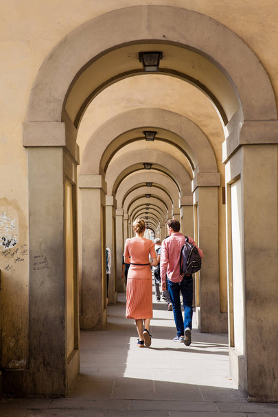 フィレンツェのヴァサリ回廊のアーチに沿って歩くカップル - 写真・画像