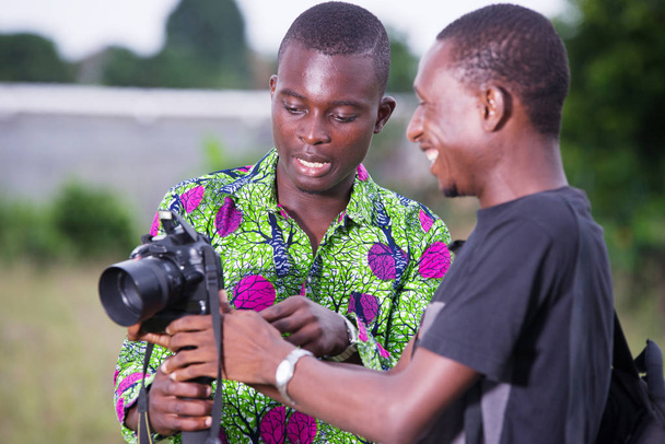 dos turistas jóvenes miran las fotos juntos en la cámara
 - Foto, Imagen