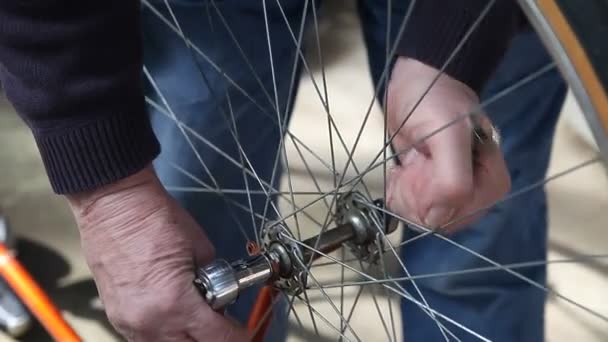 Een man neemt een fiets wiel van zijn frame - Video