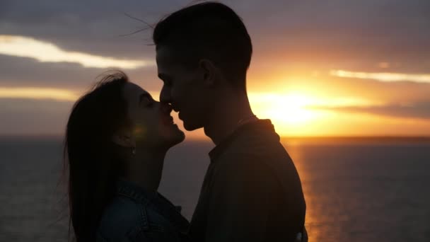 Rapaz sortudo abraçando e beijando sua linda garota na praia ao pôr do sol em câmera lenta Vista maravilhosa de um menino morena romântico abraçando e beijando sua menina mel brilhante com cabelos longos soltos no Mar Negro ao pôr do sol dourado em câmera lenta
 - Filmagem, Vídeo