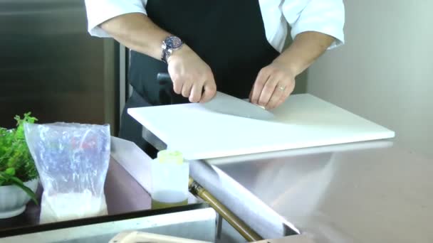 Vue en coupe des mains d'un homme tranchant un champignon avec un couteau de cuisine sur une planche à découper
 - Séquence, vidéo