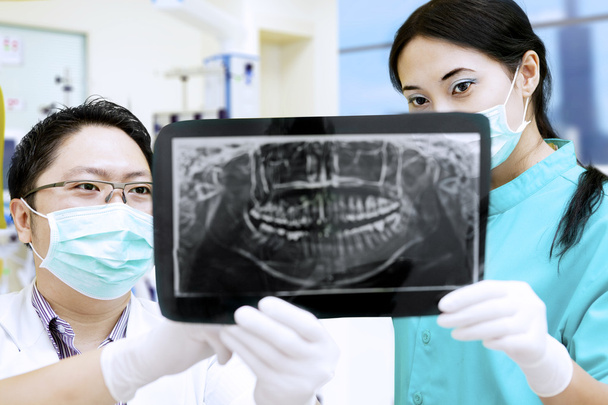 Attractive assistant and dentist looking at x-ray at hospital - Foto, imagen