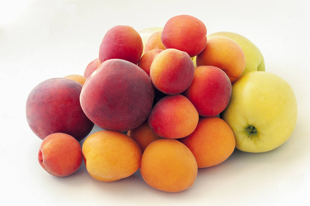 Verse sappige perziken vruchten, groene appels en rijpe abrikozen geïsoleerd op witte achtergrond. Zomer fruit concept. Close-up - Foto, afbeelding