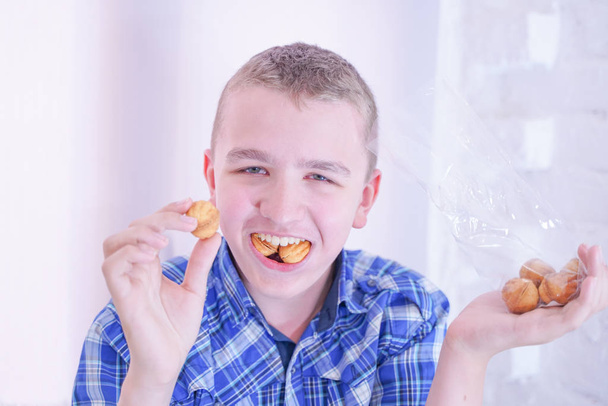 милий голодний хлопчик-підліток зі свіжими маленькими солодощами для випічки на білому фоні
 - Фото, зображення