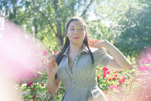 Ασιατικό κορίτσι αναπαύεται το καλοκαίρι στο πάρκο στην έντονη θερμότητα στο φωτεινό ήλιο μόνο - Φωτογραφία, εικόνα