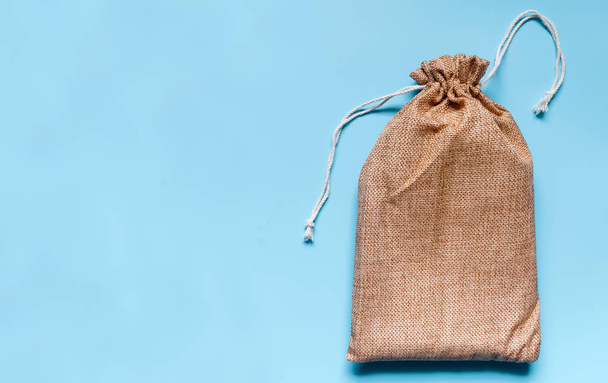 Brown cloth bag on blue background. The bag is covered with white lines. - Фото, изображение