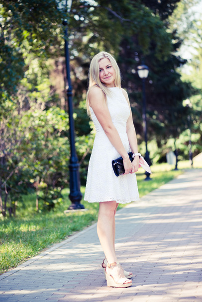 Beautiful young blond woman in a white dress outdoors - Foto, imagen
