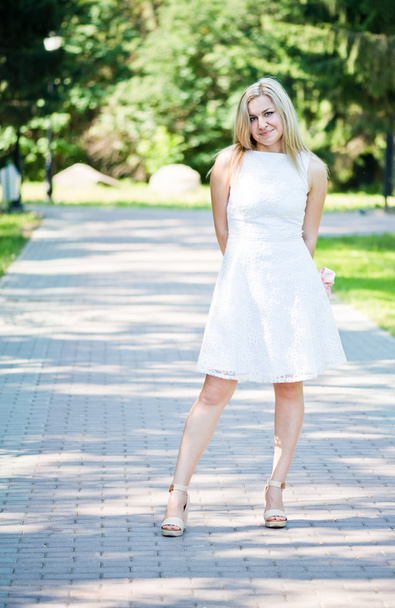 Beautiful young blond woman in a white dress outdoors - Photo, Image