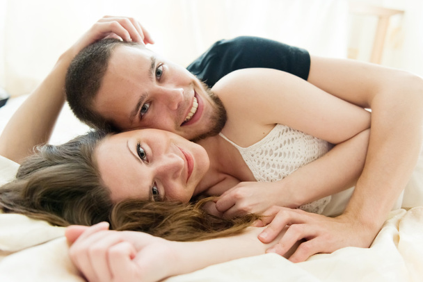 Bella coppia che si abbraccia sul loro letto a casa
 - Foto, immagini