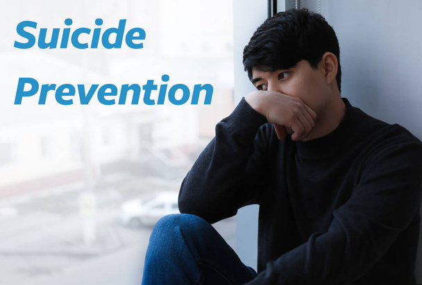 Depressed Asian man sitting near window. Suicide prevention concept - Photo, Image