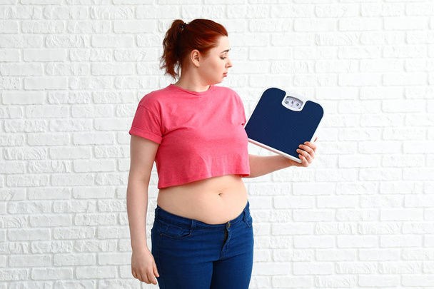 Избыточный вес женщины с весами на белом фоне. Концепция потери веса
 - Фото, изображение