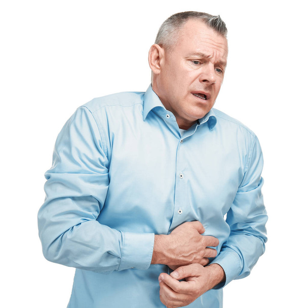 Csinos középkorú férfi szenved gyomorfájás fehér alapon - Fotó, kép