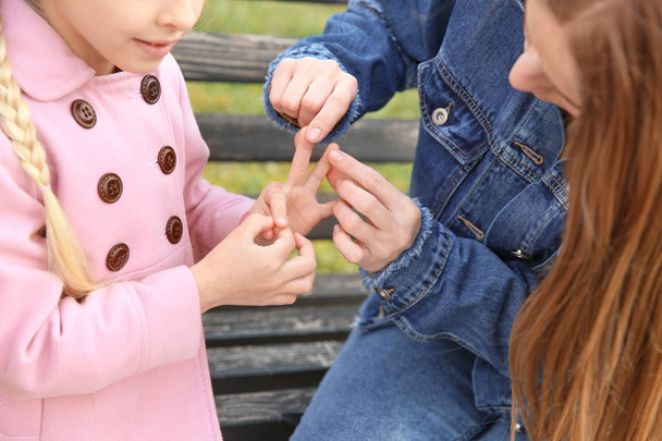 Mother teaching her deaf mute daughter to use sign language outdoors - Photo, Image