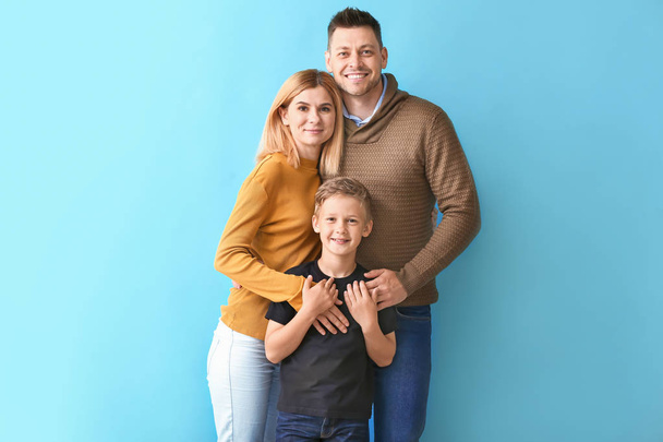 Happy couple with little adopted boy on color background - Photo, Image