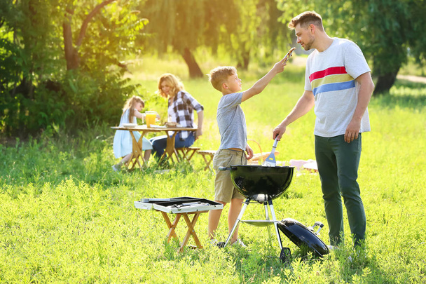 Father with son cooking tasty food on grill outdoors - Photo, Image