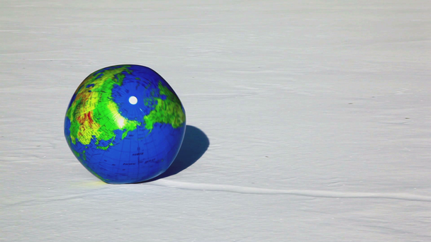Inflated ball with earth texture roll by snow - Imágenes, Vídeo