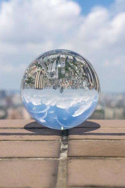 bola de vidrio sobre un fondo de la ciudad con un cielo azul y nubes blancas
 - Foto, imagen