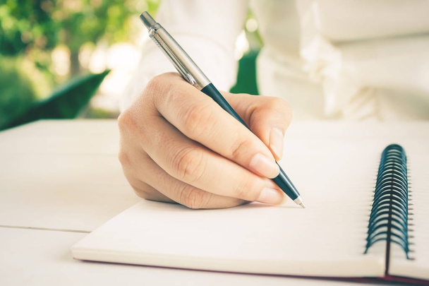 白いノートにペンを書いて女性の手。コピースペース付き. - 写真・画像