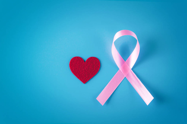 Pink ribbon and red heart on a blue background. Blank copy space. - Fotografie, Obrázek