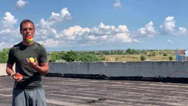 Egy férfi juggles golyó a tetőn egy ház - Felvétel, videó