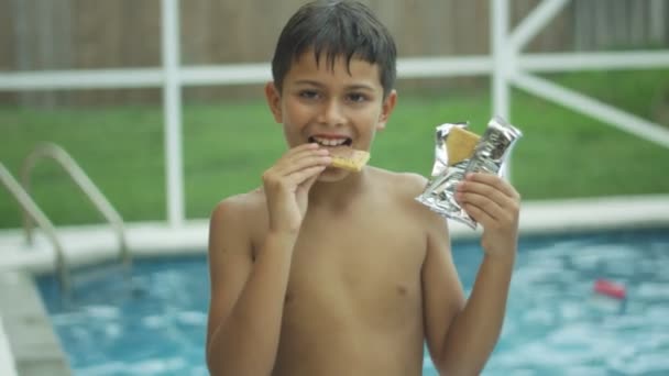 Sevimli bir çocuk yeme ve bir yüzme havuzunun önünde gülümsüyor yavaş hareket - Video, Çekim