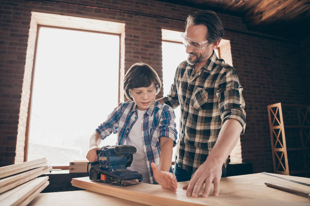 Two nice focused inspired cheerful creative person master builder dad teaching son explaining training fixing repairing building construction at studio loft industrial style brick interior - Foto, Imagen