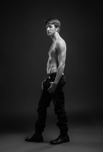 Volledige lengte portret van een sexy jonge man in jeans en shirtless poseren in Studio. - Foto, afbeelding
