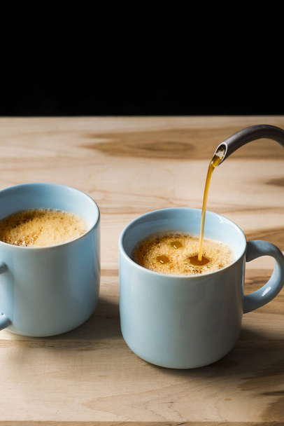 Γεμίστε τον καφέ σε δύο μπλε φλιτζάνια καφέ. - Φωτογραφία, εικόνα