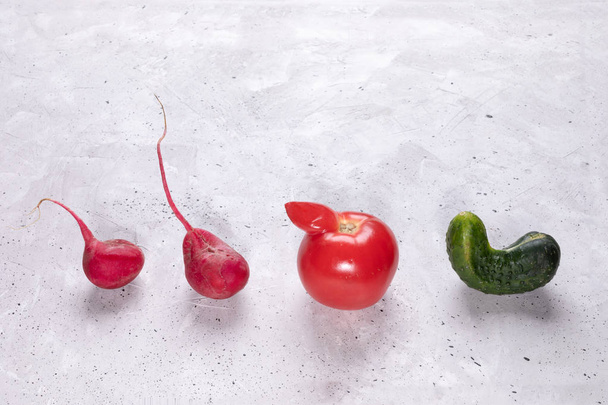 Four ugly vegetables: tomato, cucumber and radish laid out in row on concrete background.  - Zdjęcie, obraz