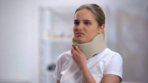 Young woman in foam cervical collar feeling sharp pain in neck, trauma result - Fotografie, Obrázek