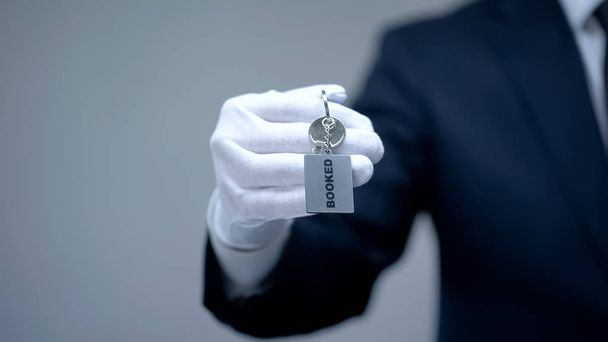 Booked word on keychain in receptionist hand, luxury hotel services, closeup - Foto, Bild