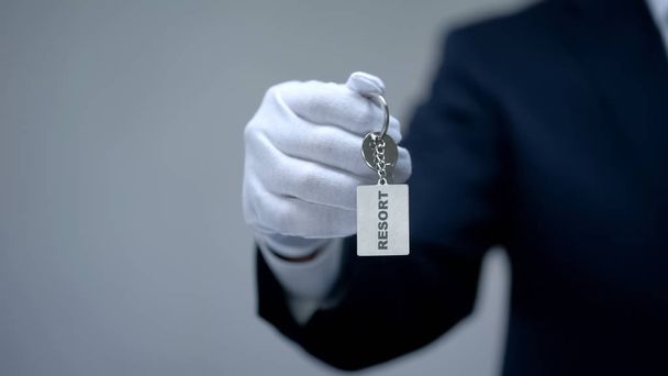 Resort word on keychain in receptionist hand, luxury housing rentals on vacation - Foto, Bild