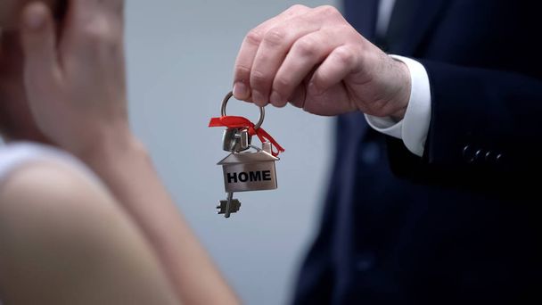 Rich businessman giving key with Home inscription to happy female, gift to lover - Foto, Imagen