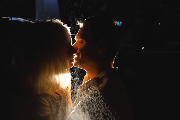 Young happy couple in love kissing in night under rain. Photo with flash effects - Photo, Image