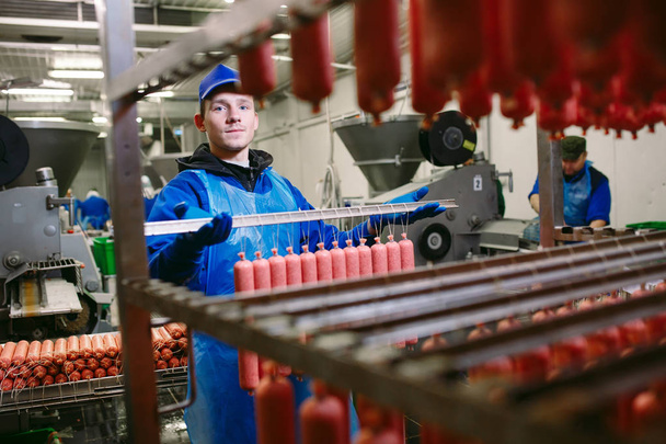 Retrato de carniceros procesando embutidos en fábrica de carne
 - Foto, Imagen