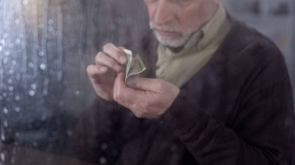 Poor retired man counting money in hand, economic crisis, financial problem - Foto, Bild