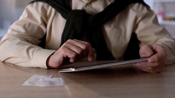 Hombre usando cheques guardados y tableta para pagar impuestos de compra, primer plano de la banca en línea
 - Foto, imagen