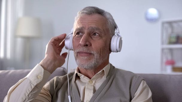 Old man in headphones listening to romantic song, remembering love feelings - Fotó, kép