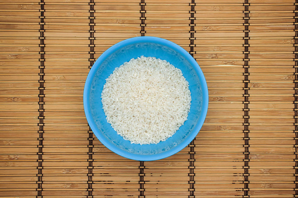 White rice in blue dish on the wooden table  - Фото, изображение