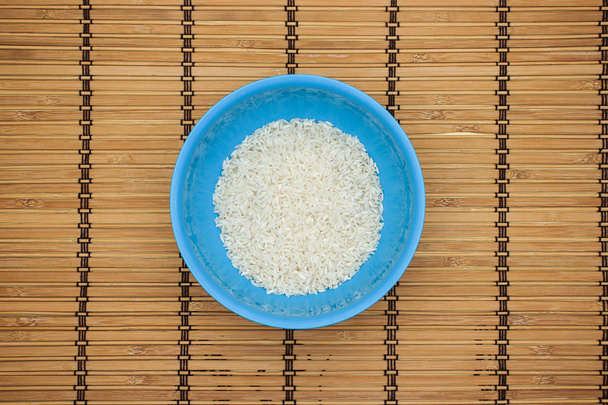 White rice in blue dish on the wooden table  - Фото, изображение