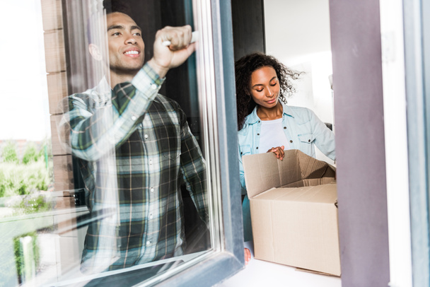афроамериканський чоловік відкриває вікно в той час як дружина відкриває коробку
  - Фото, зображення